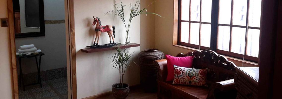 Ein gemütliches Zimmer mit einer Holzsofa, einer Topfpflanze und einem Regal mit Dekoration.