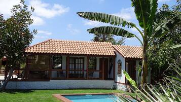 A house with a tiled roof, a swimming pool, and lush greenery.
