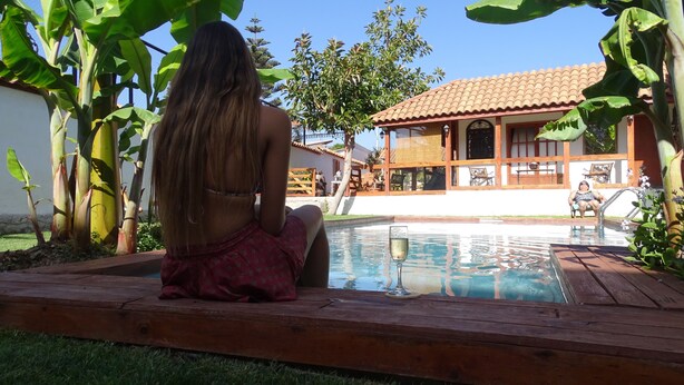 A person sitting by a pool with a house in the background. - Primera Hacienda Hotel Boutique (La Serena)