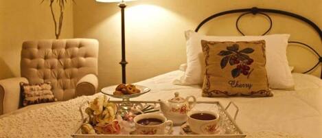 A neatly arranged bedroom with a bed, a bedside table with a tray of breakfast items, a lamp, and a decorative pillow.