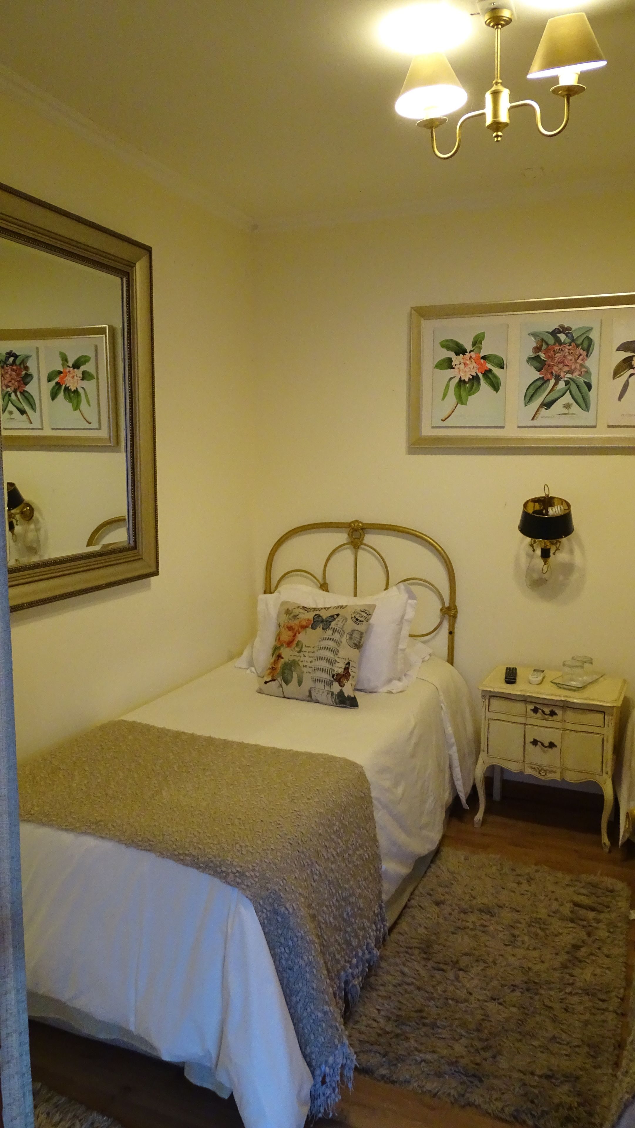 Une chambre à coucher comprenant un lit, une table de chevet, une commode, un miroir et des œuvres d’art accrochées au mur.