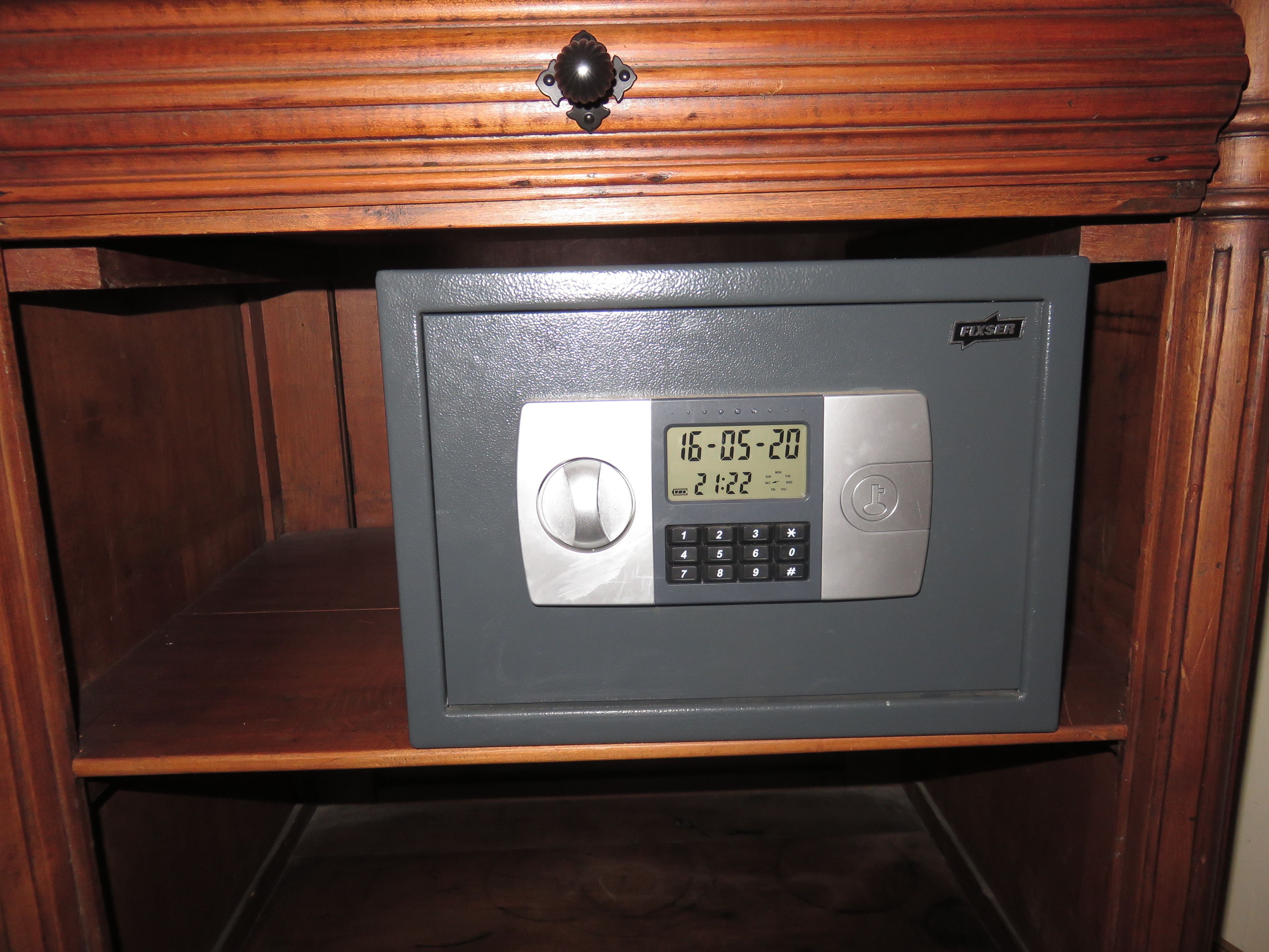 A safe deposit box under a wooden cabinet with a digital lock and keypad.