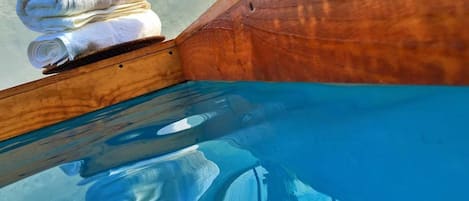 Bordo in legno di una piscina con una pila di asciugamani bianchi.