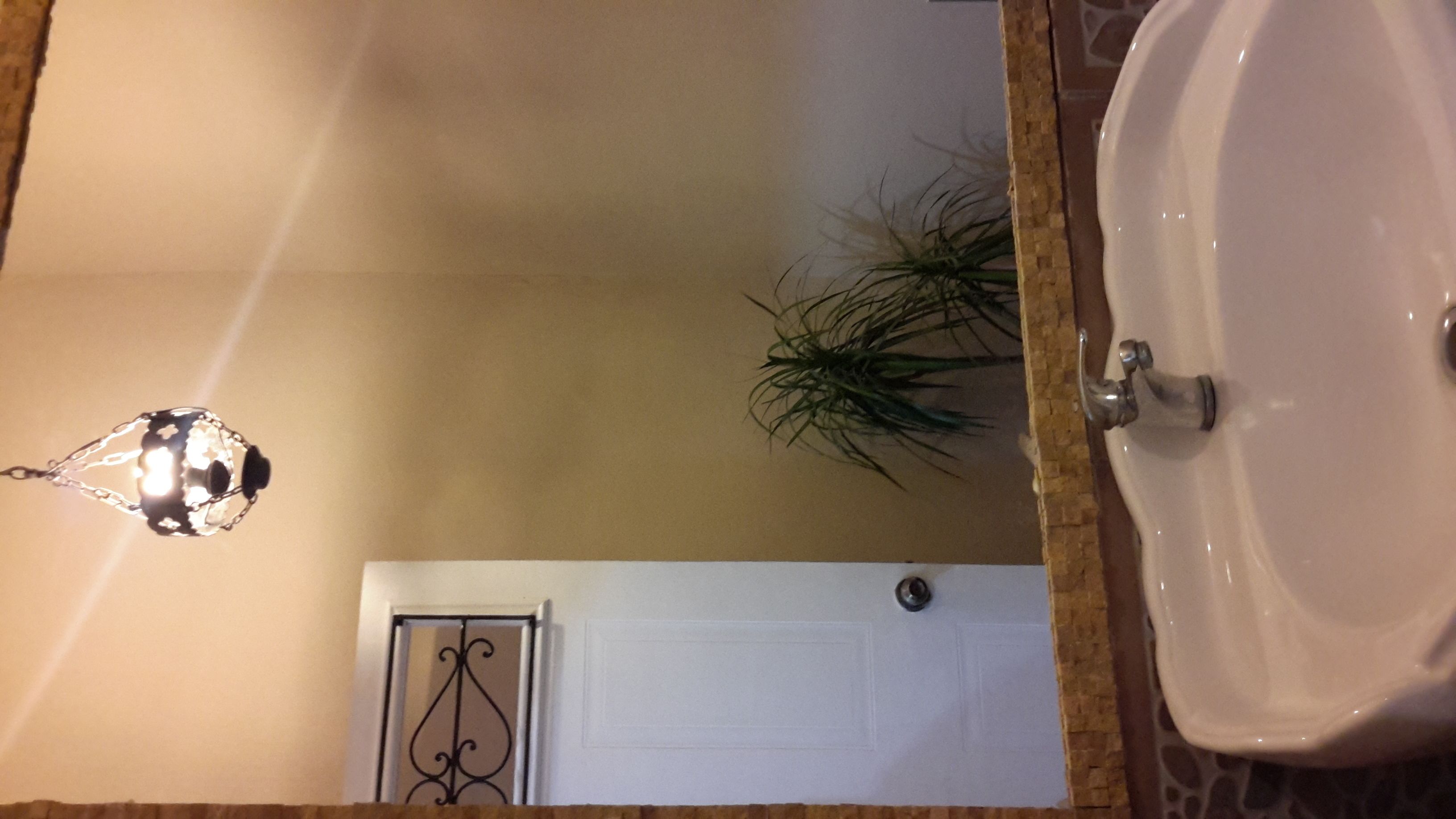 A bathroom with a white sink, a mirror, and a hanging light fixture.