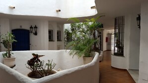 A courtyard with white walls, potted plants, a blue door, and a tiled floor. - Resort Medina del Zoco (Mijas)