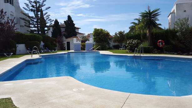 A swimming pool with a clear blue water, surrounded by a concrete deck, and a lifebuoy hanging on the right side. - Resort Medina del Zoco (Mijas)