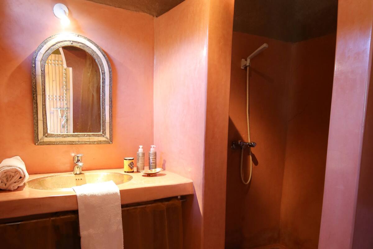 A bathroom with a sink, mirror, and shower.