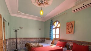 Une chambre avec deux lits, un sol à carreaux, un plafond décoratif et une fenêtre avec des rideaux.