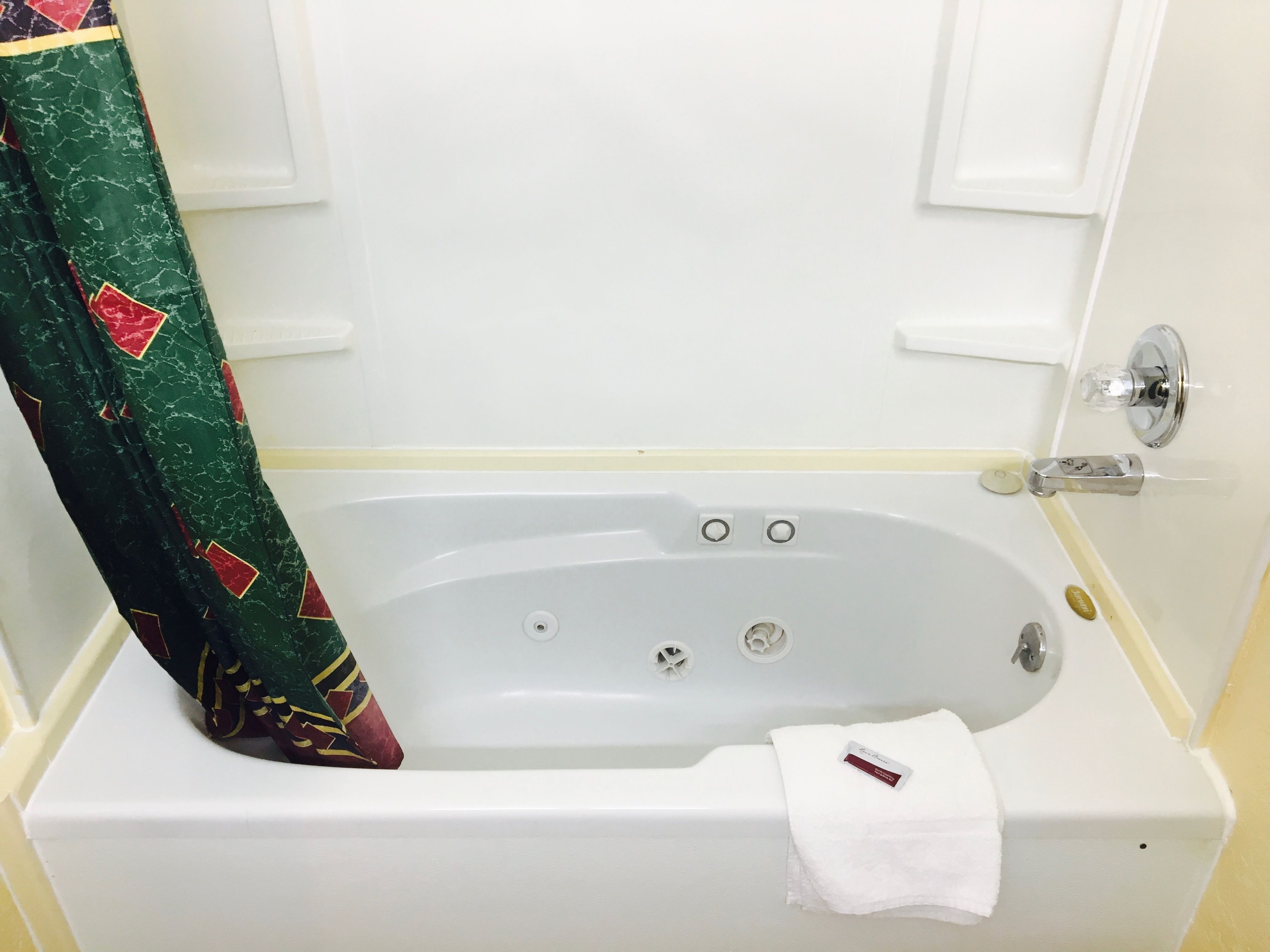 A white bathtub with a white towel and a bottle of shampoo.