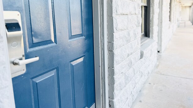 A blue door with a mail slot, adjacent to a white brick wall. - Relax Inn Lawton (Lawton)