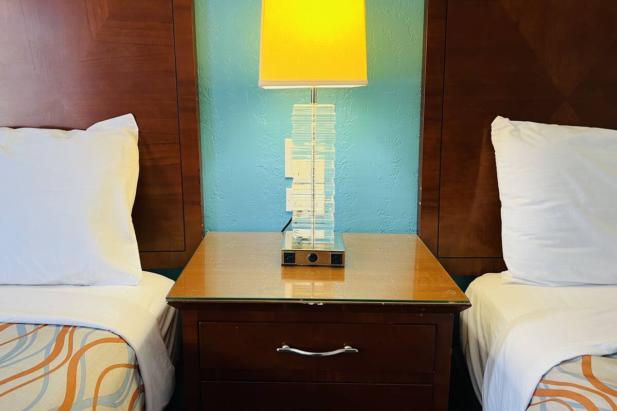 Habitació d'hotel amb una nitrera de fusta, una làmpada i un calaix.