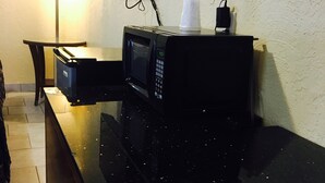 A kitchen area with a microwave, a small table, and a cabinet. - Relax Inn Lawton (Lawton)
