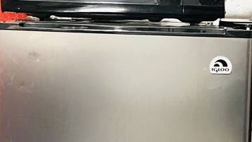 A stainless steel refrigerator with a microwave on top.