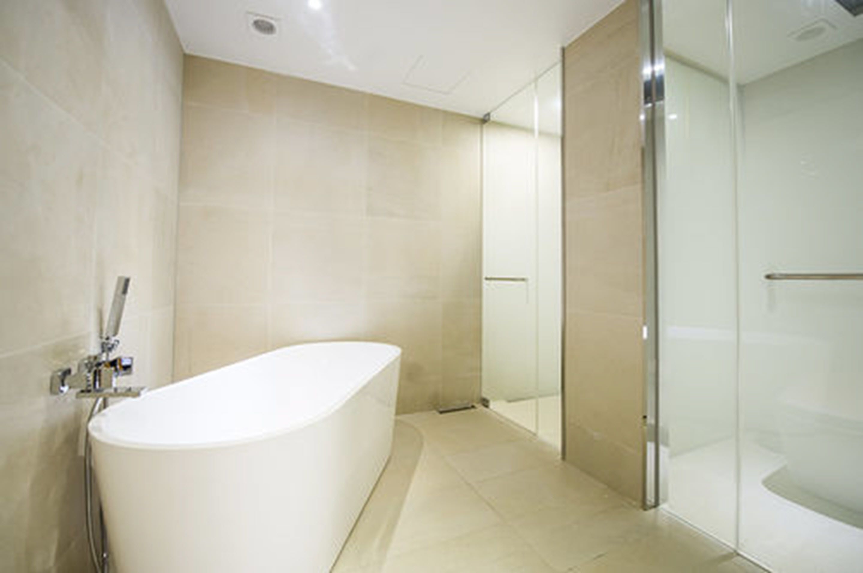A modern bathroom with a freestanding bathtub, a glass shower enclosure, and tiled walls.