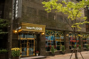 A hotel entrance with a sign reading "hotel FLOCE," large windows, and potted plants. - Floce Hotel (Bucheon)