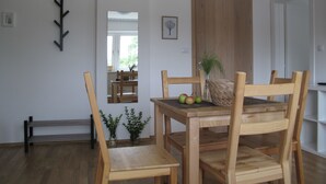 A dining area with a wooden table and chairs, a vase with plants, and a mirror reflecting the room. - Guesthouse Bor (Plitvicka Jezera)