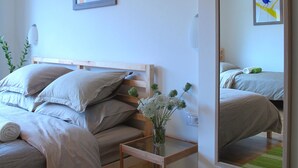 A bedroom with a bed, pillows, a bedside table with a vase of flowers, a mirror, and two framed pictures on the wall. - Guesthouse Bor (Plitvicka Jezera)