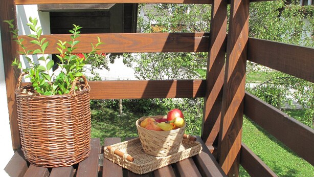 A wooden deck with a wicker basket and a woven placemat holding a fruit bowl. - Guesthouse Bor (Plitvicka Jezera)