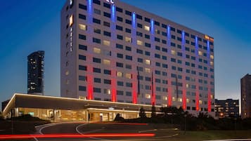 Een meerhoog hotel met een opvallend ‘NOVOTEL’ bord, een modern architectuurontwerp en een goed verlichte entree.