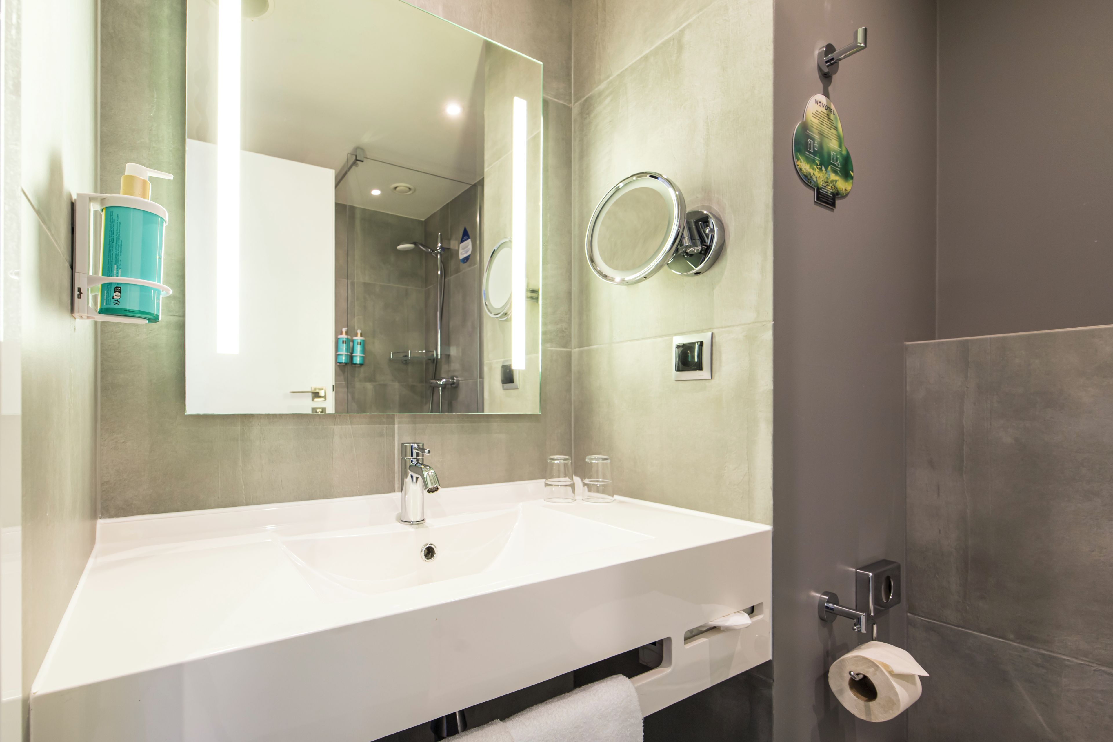 Een moderne badkamer met een grote spiegel, een wit wastafelmeubel en een douchegedeelte.