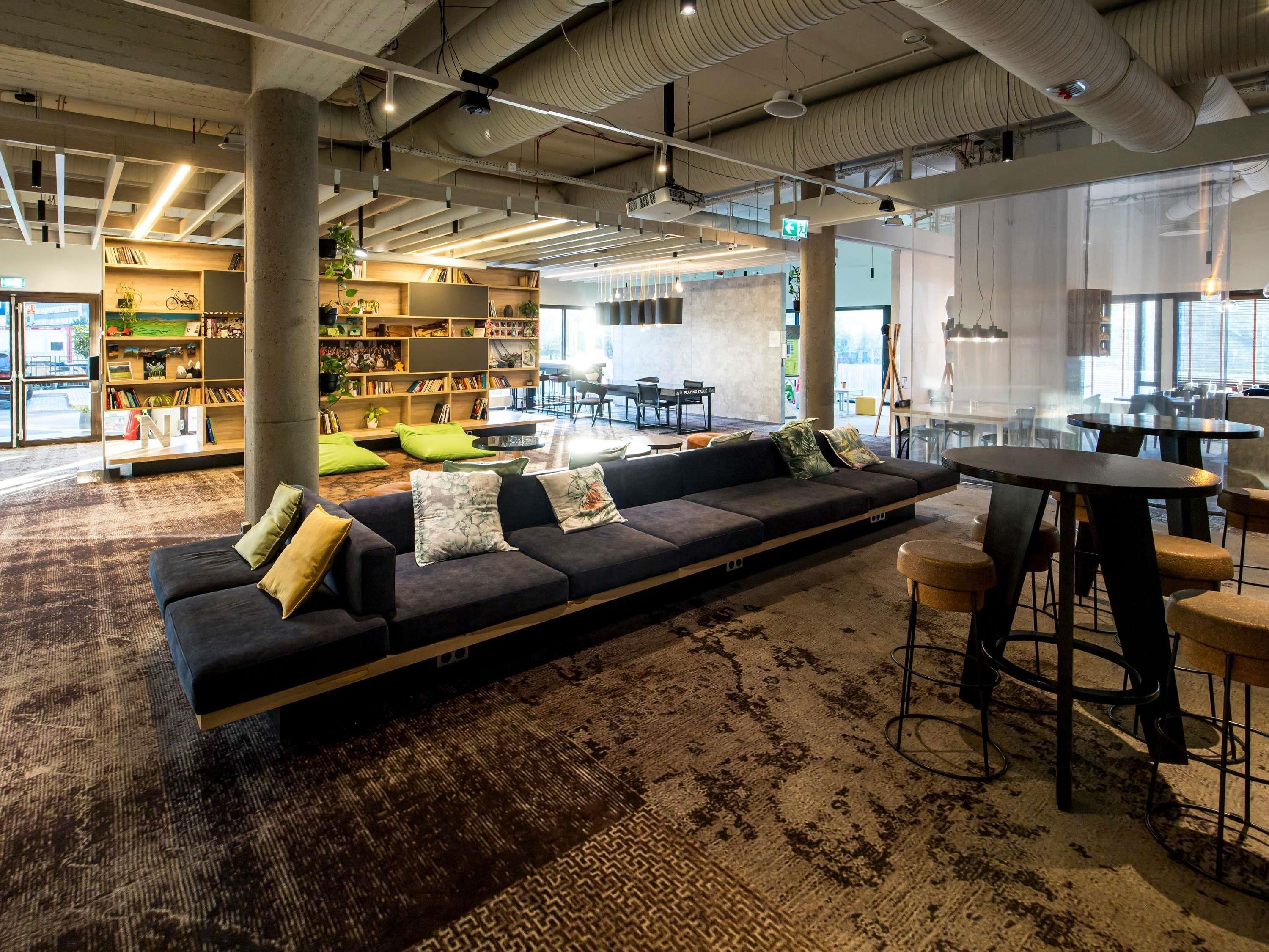 A modern lounge area with a sectional sofa, a bar area, and a bookshelf filled with books and decorative items.