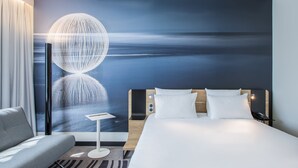 A modern hotel room with a large bed, a sofa, a nightstand, and a wall mural of a night sky. - Novotel Wroclaw Centrum (Wroclaw)