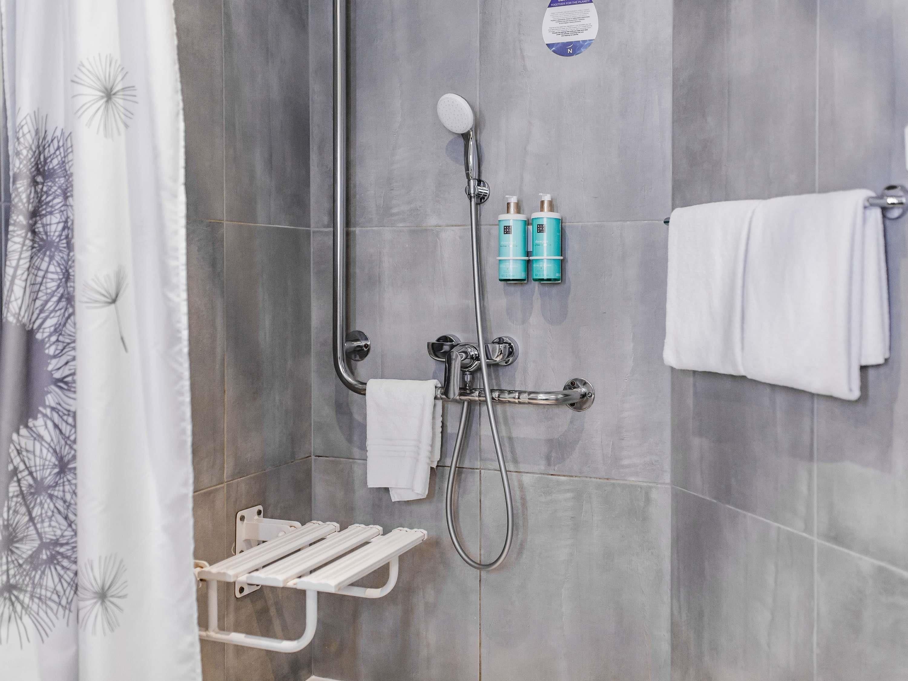 Ein Duschbereich mit Handbrause, Handtuchhalter und Ablagefläche für Toilettenartikel.