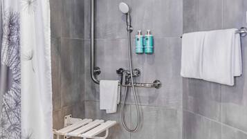 Ein Duschbereich mit Handbrause, Handtuchhalter und Ablagefläche für Toilettenartikel.