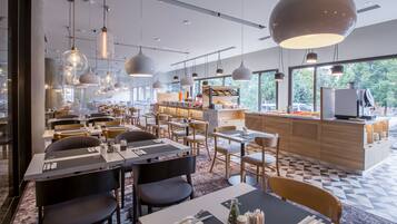 A modern restaurant with multiple dining areas, pendant lighting, and a view of the outdoors.