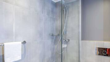 A modern shower with a glass door, a towel rack, and a wall-mounted control panel.