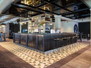 Eine Bar mit Theke, Hockstühlen und Regalen voller Flaschen.