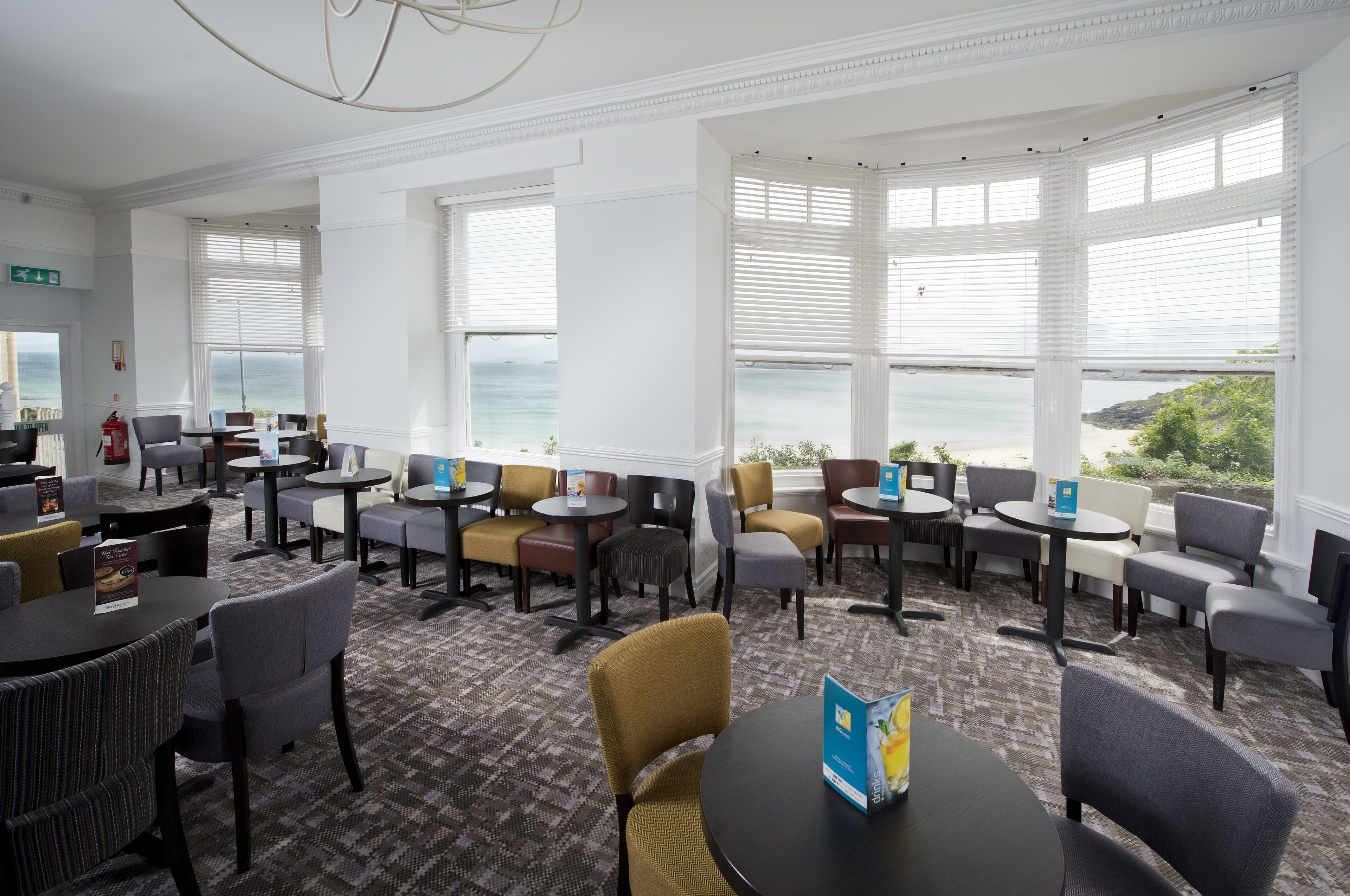A hotel lobby with multiple seating areas, a fire extinguisher, and a view of the sea.