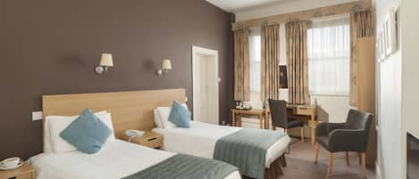 A hotel room with two beds, a desk, a chair, a TV, and a phone on the nightstand.
