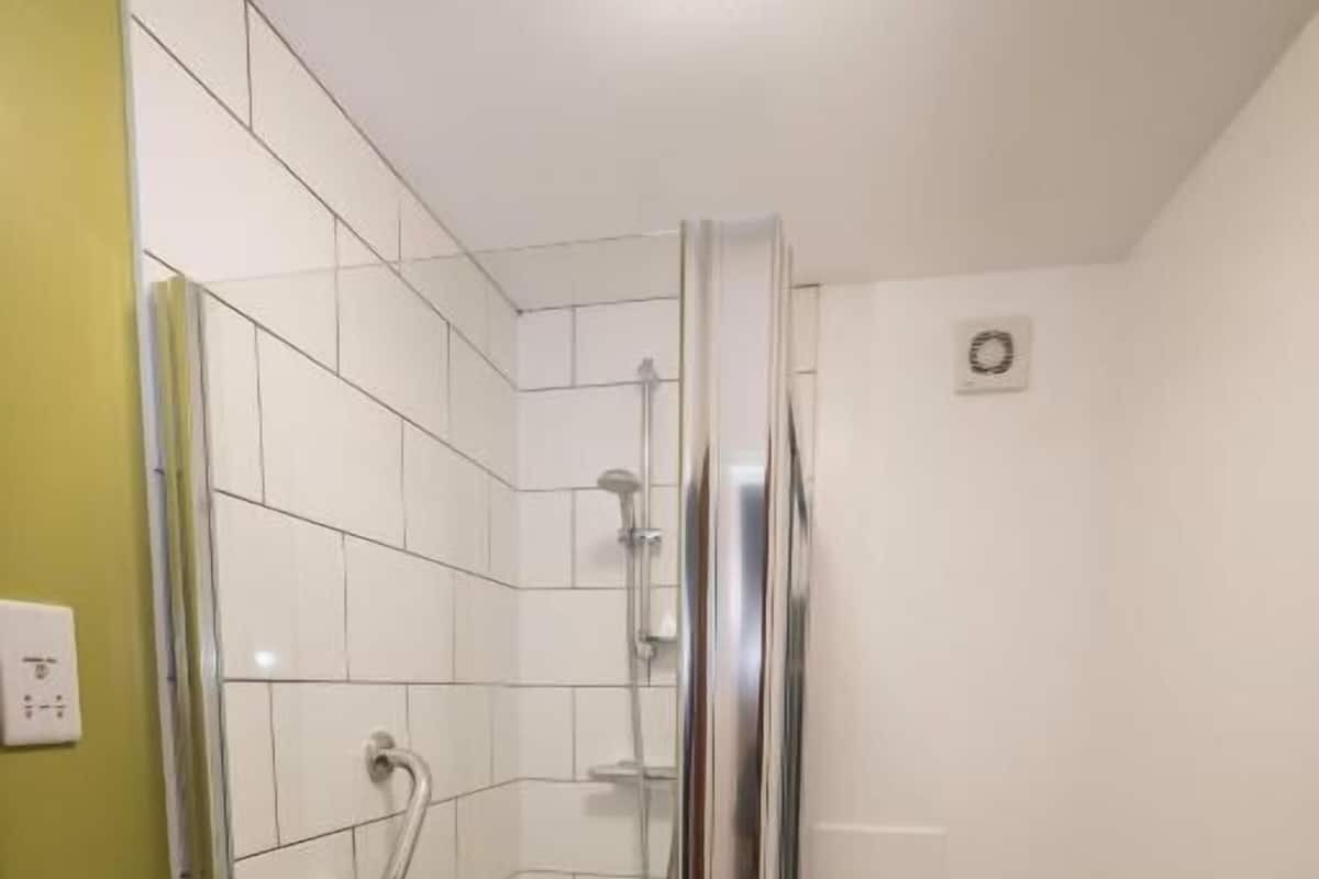 Un baño pequeño con ducha, inodoro y lavabo.
