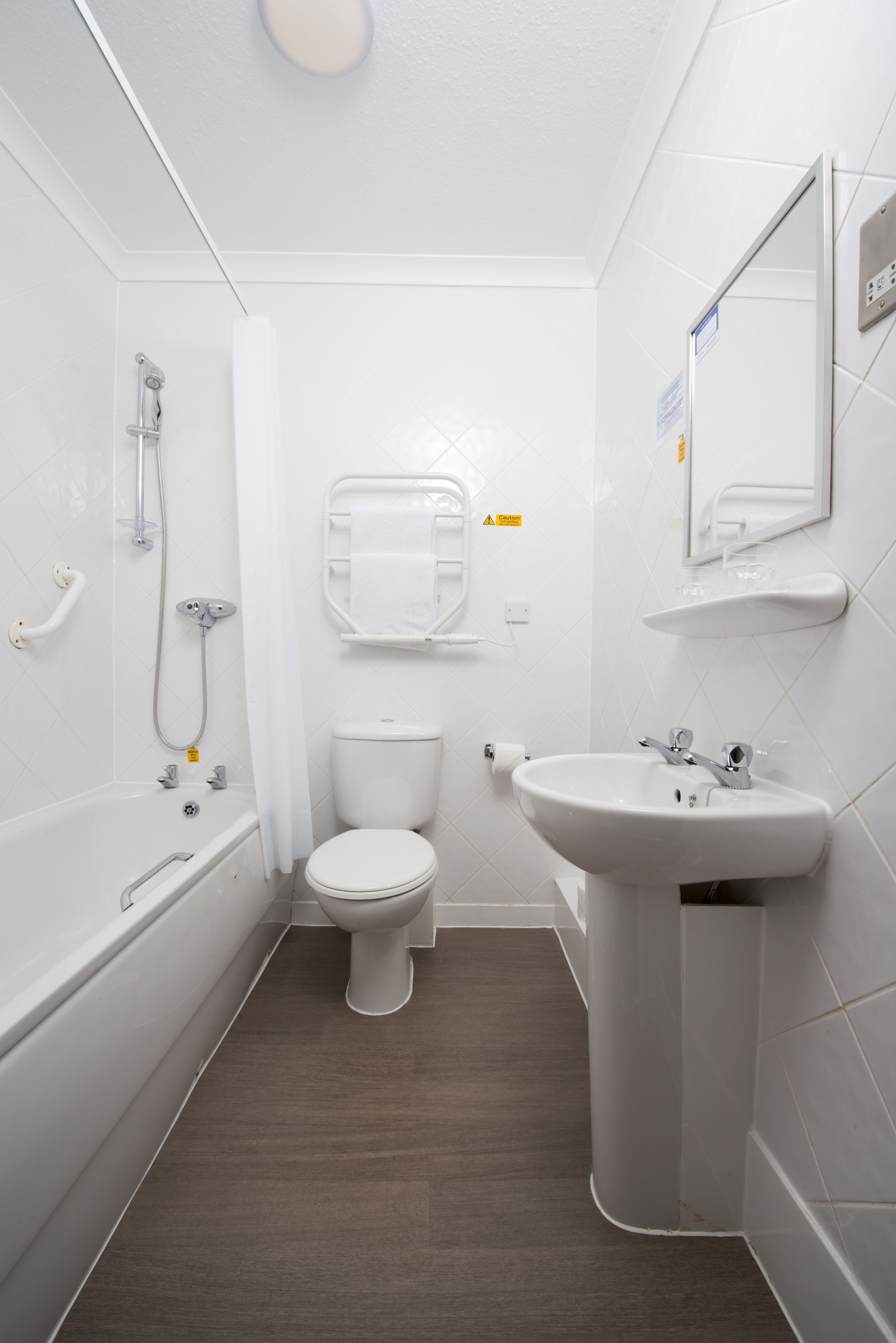 A small, modern bathroom with a white toilet, a sink, and a bathtub.