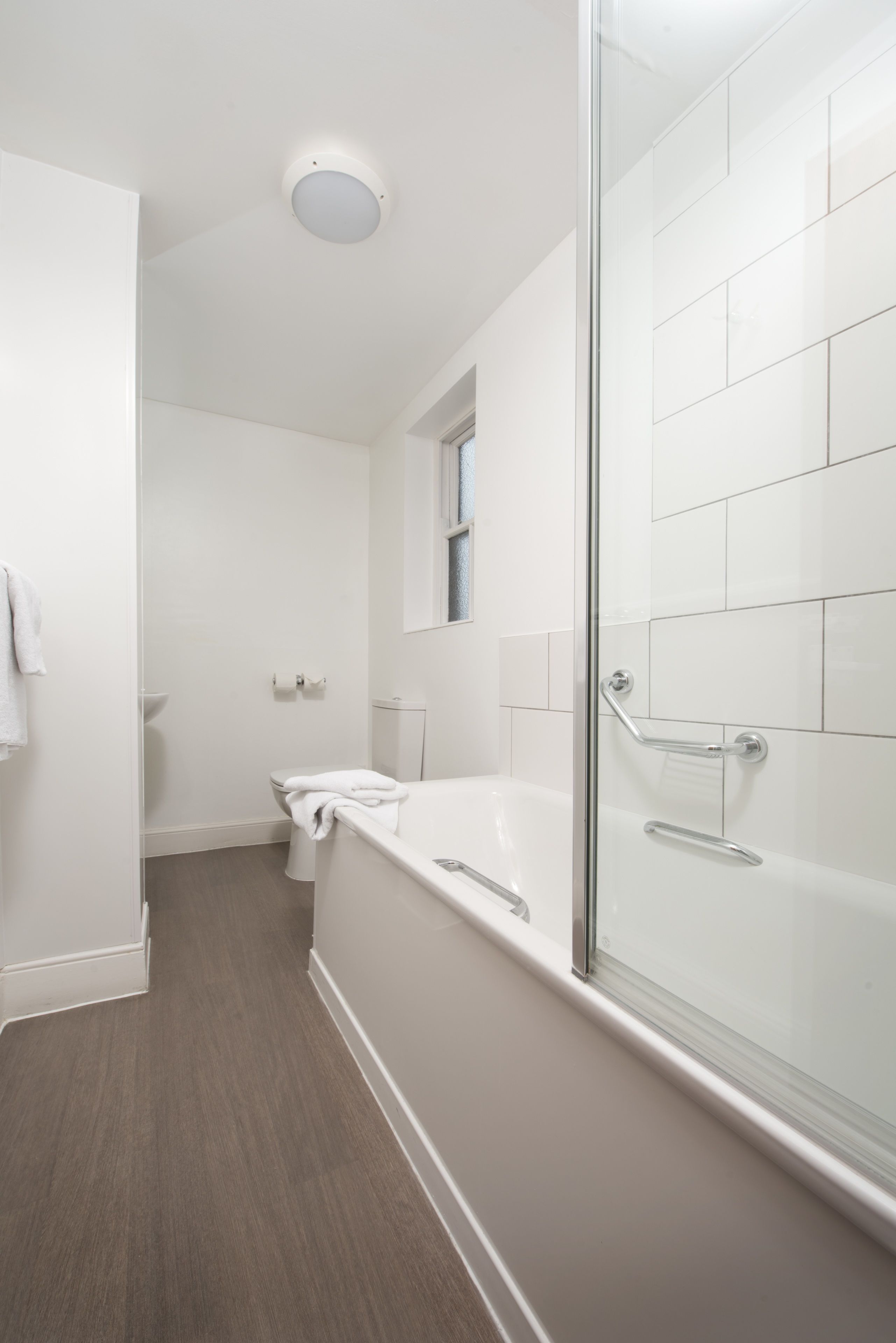 A modern bathroom with a glass shower enclosure, a white bathtub, and a toilet.