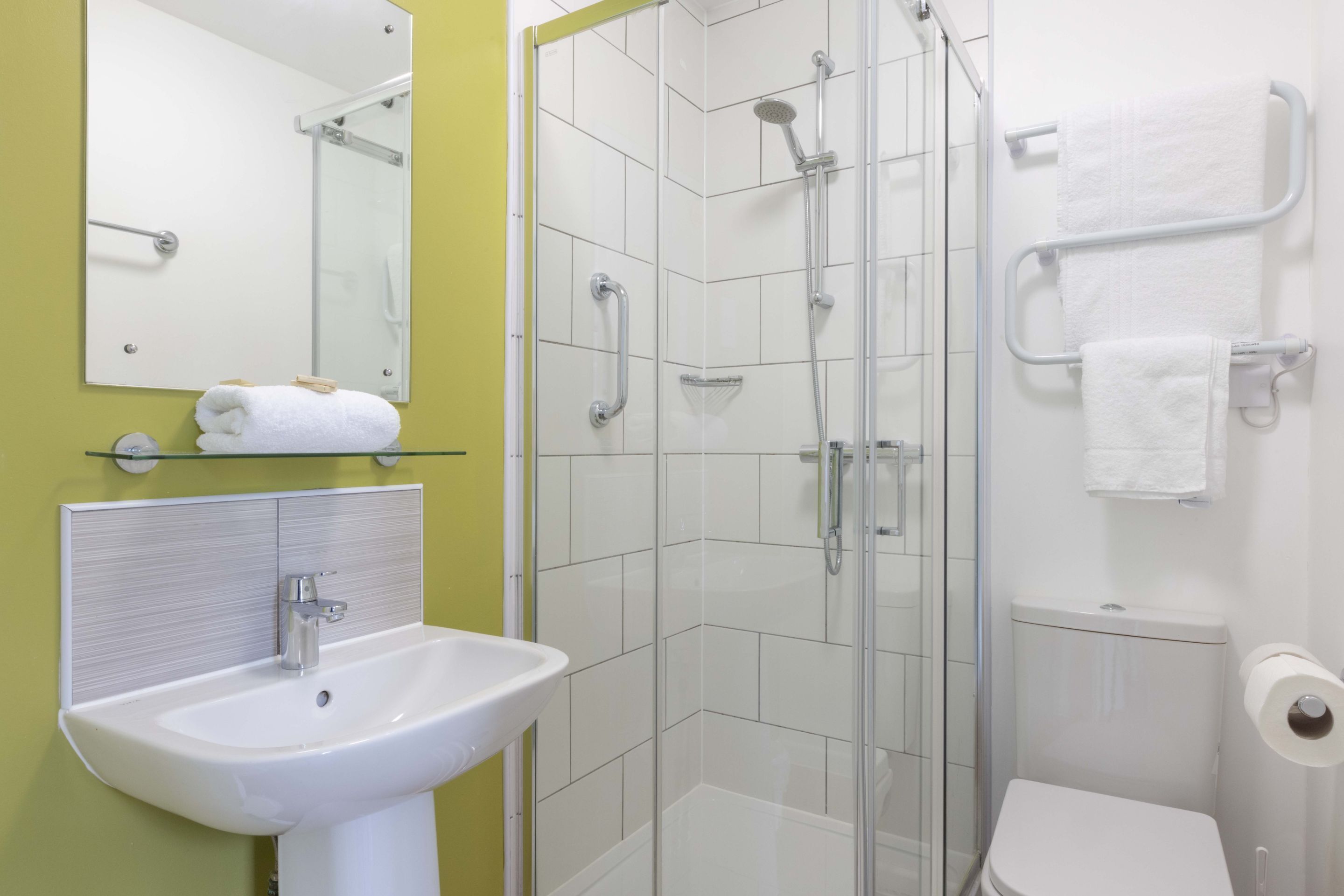 A bathroom with a glass-enclosed shower, a white sink, and a toilet.