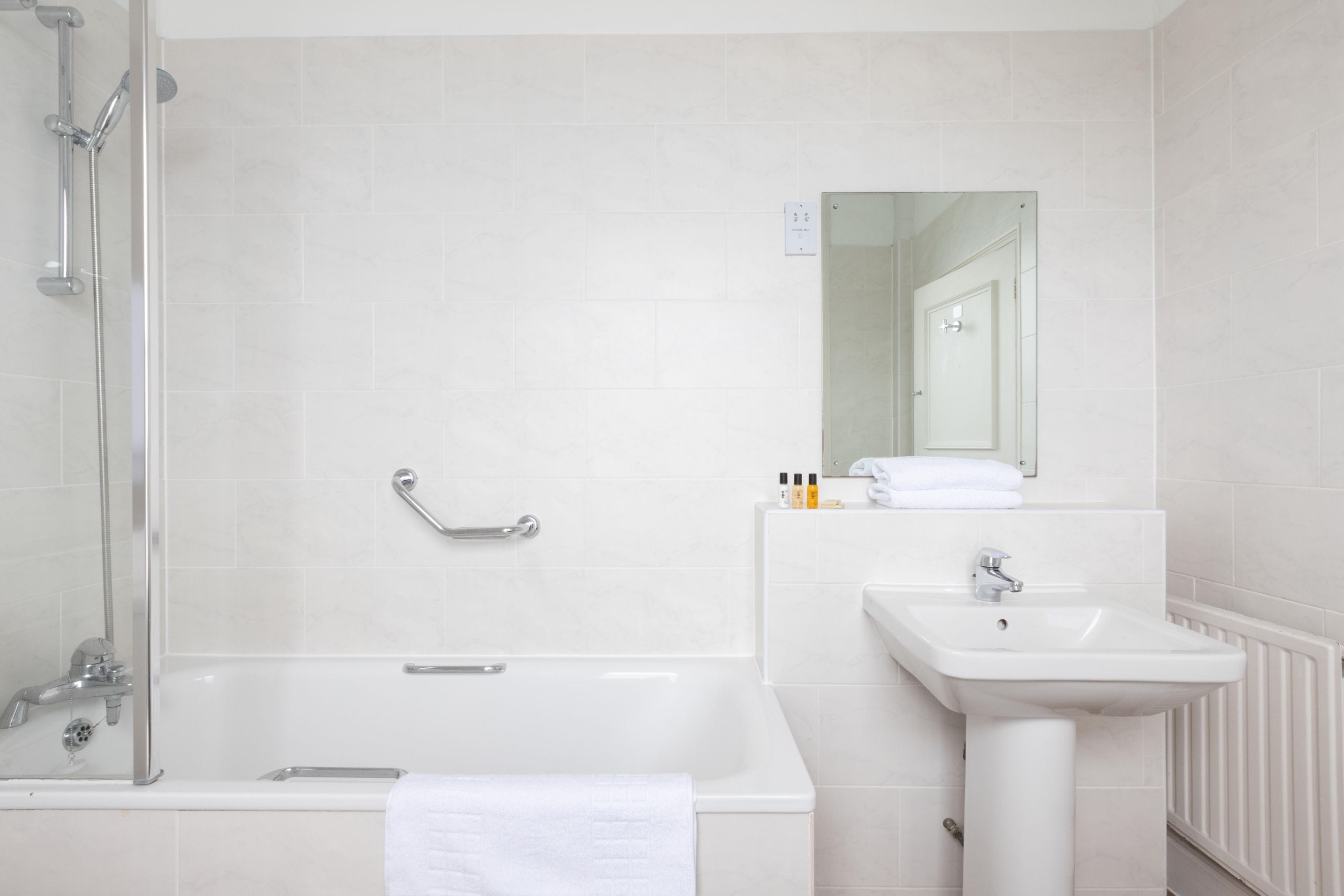 Ein modernes Badezimmer mit einer ein Glaswand abgetrennten Dusche, einer weißen Badewanne und einem Standwaschbecken.