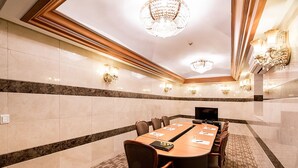 A conference room with a long table, chairs, a television, and wall sconces. - Korea Tourist Hotel (Suwon)