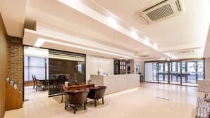 A spacious lobby with a reception desk, leather chairs, a dining area, and large windows offering views. - Korea Tourist Hotel (Suwon)