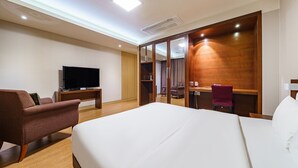 A hotel room with a large bed, a TV, a desk, and a chair. - Korea Tourist Hotel (Suwon)