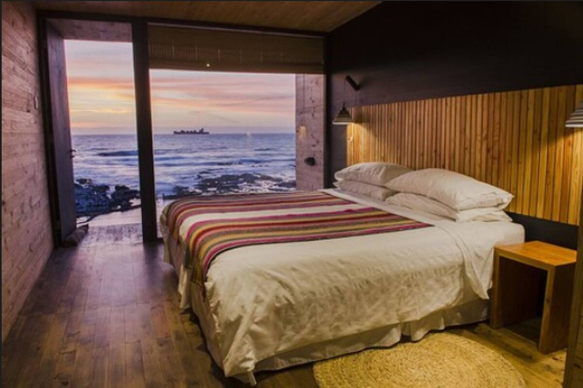 Un dormitorio con una cama grande, paredes de madera y vista al océano.