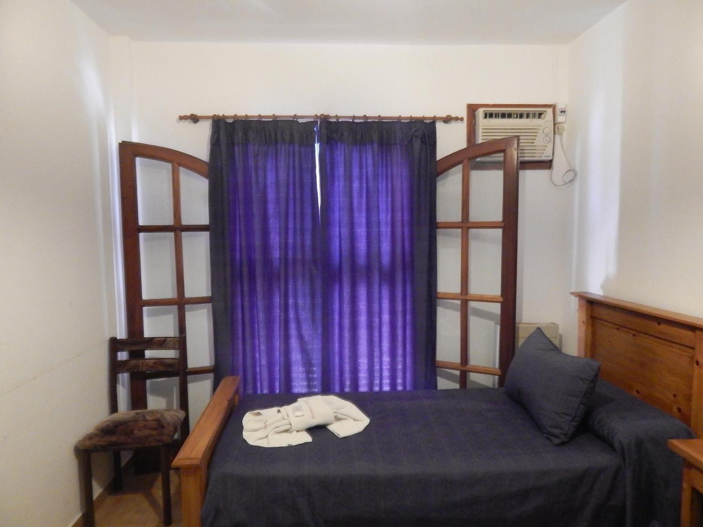 Un alojamiento pequeño y de una sola habitación, con cama, una silla y una mesita.