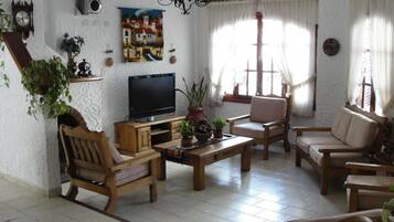 A cozy living room with a television, wooden furniture, and decorative items.