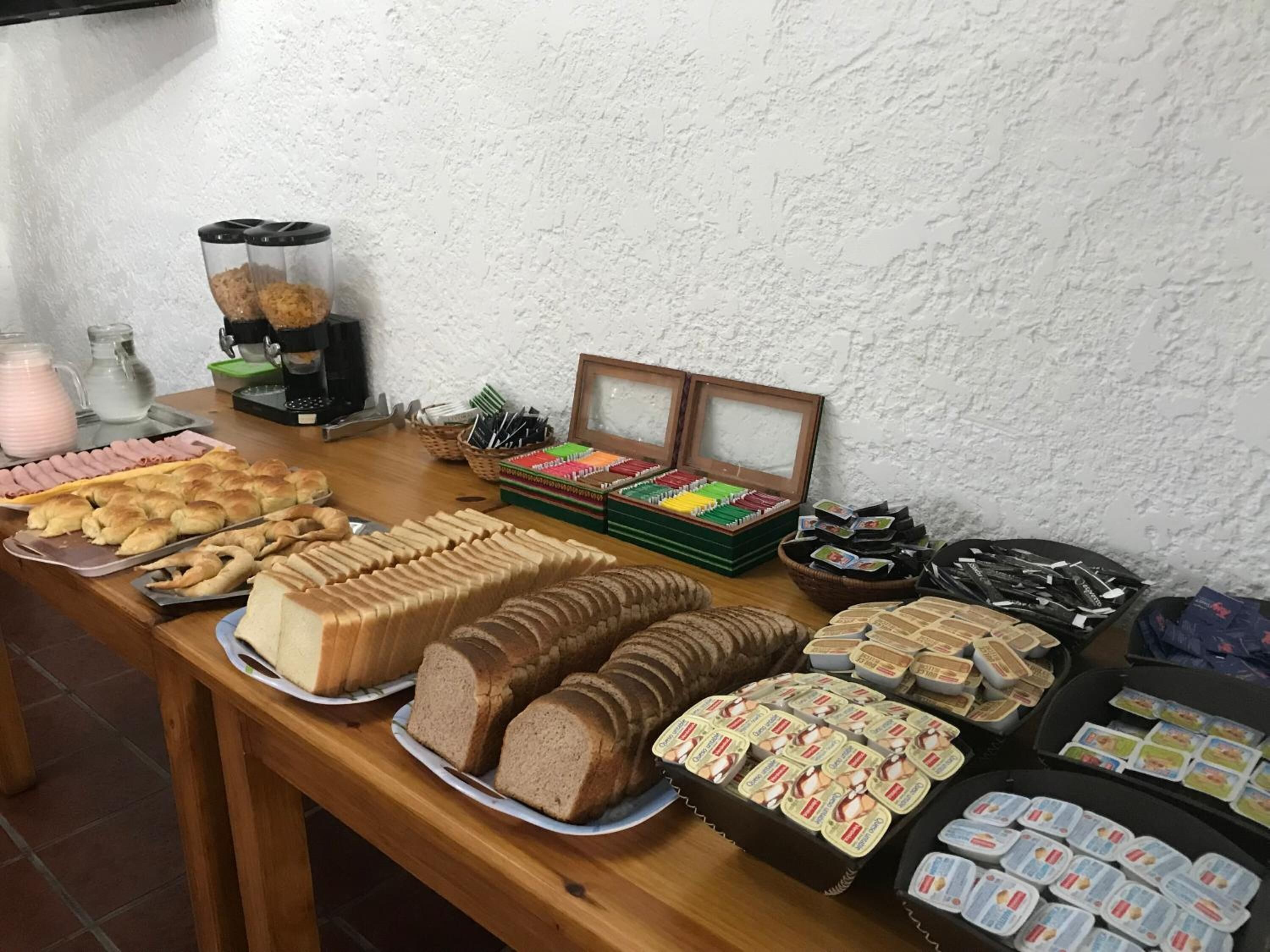 Un tavolo da buffet con diversi cibi tra cui pane, pasticcini e prodotti confezionati.