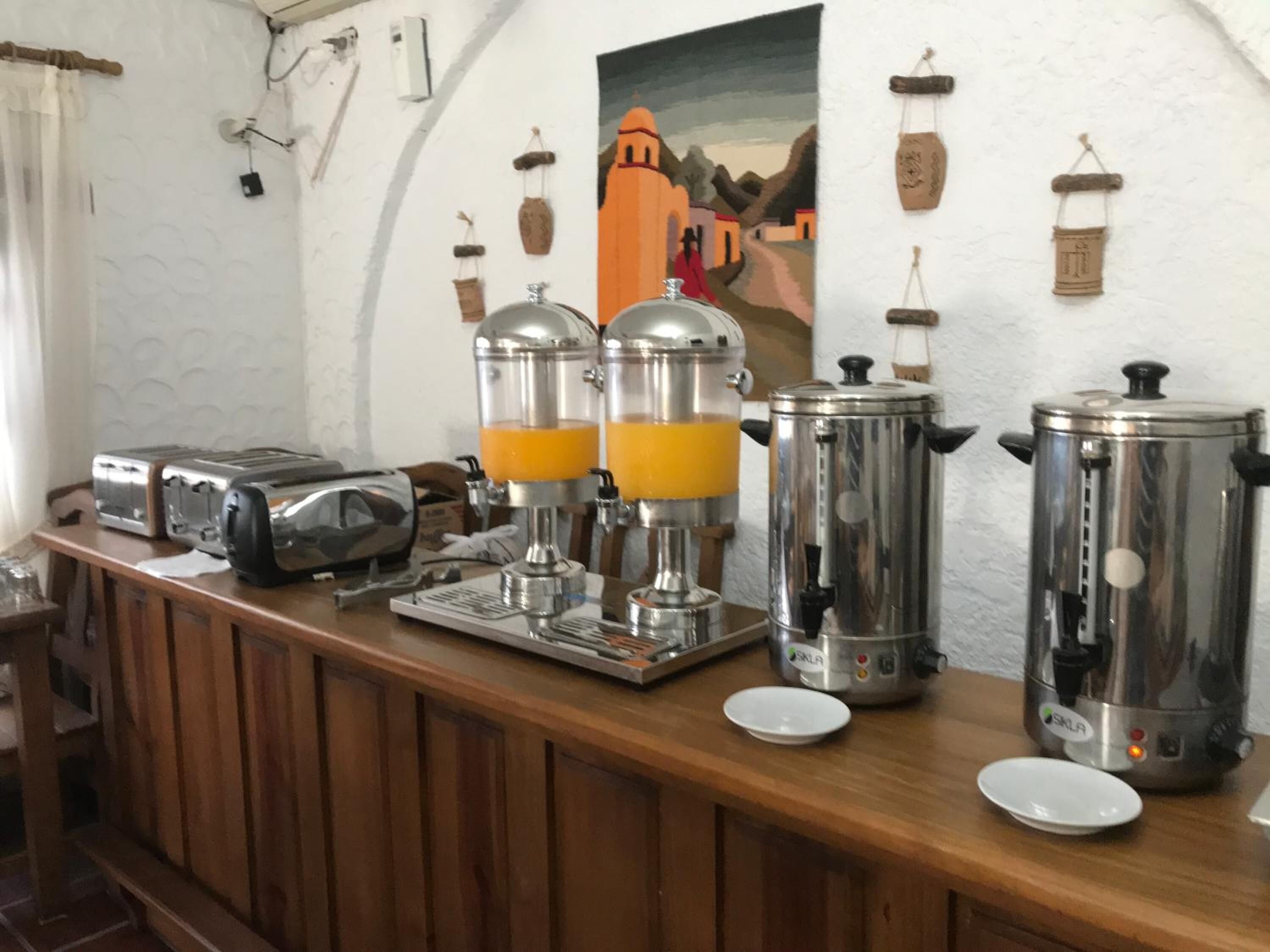 A breakfast bar with two coffee makers, a toaster, and a plate.