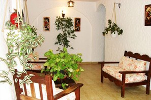 Relax in this traditional room with a wooden bench, floral cushion, and lush greenery.