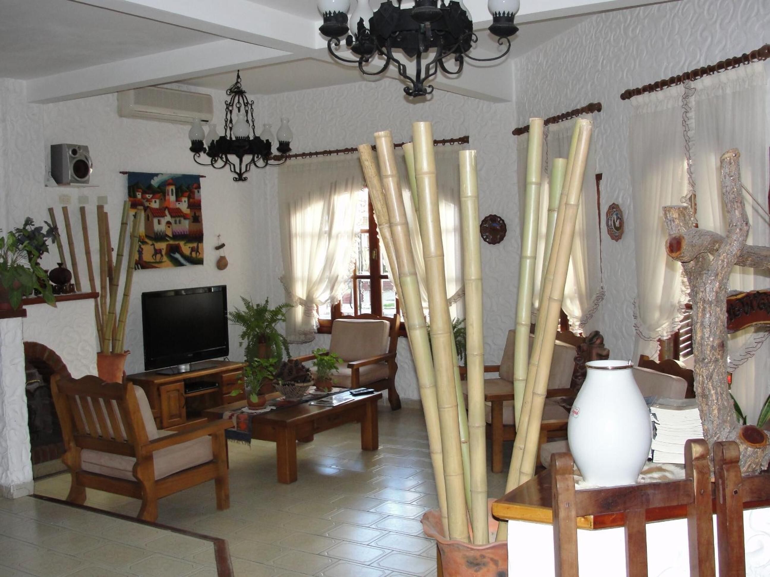 A living room with a TV, wooden furniture, bamboo decorations, and a chandelier.