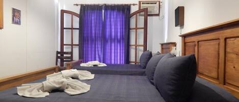Une pièce comprenant un lit, une chaise, un téléviseur et une fenêtre avec des rideaux.