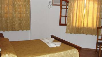 Un dormitorio con cama, una silla de madera y cortinas.